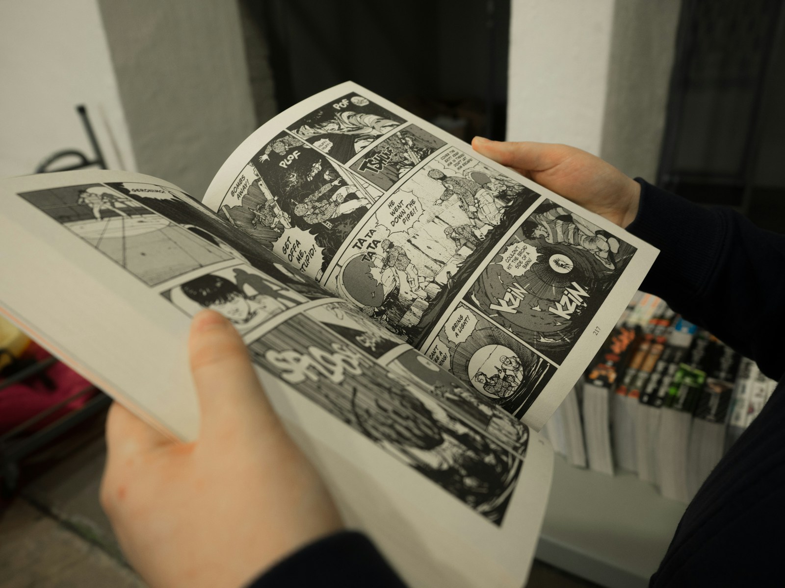 A person holding an opened manga book. This person is on their way in learning how to be an adult with this blog post.