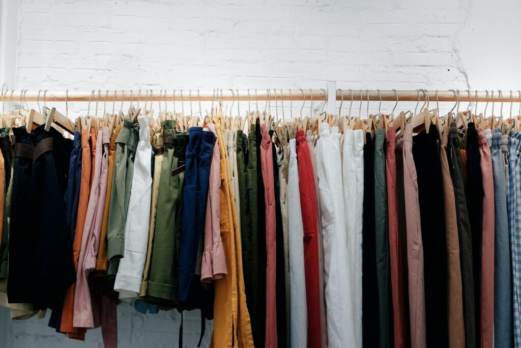 Assorted-color clothes lot hanging on wooden wall rack.