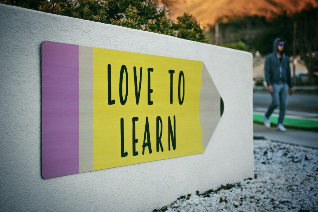 "love to learn" pencil signage on wall near walking man.